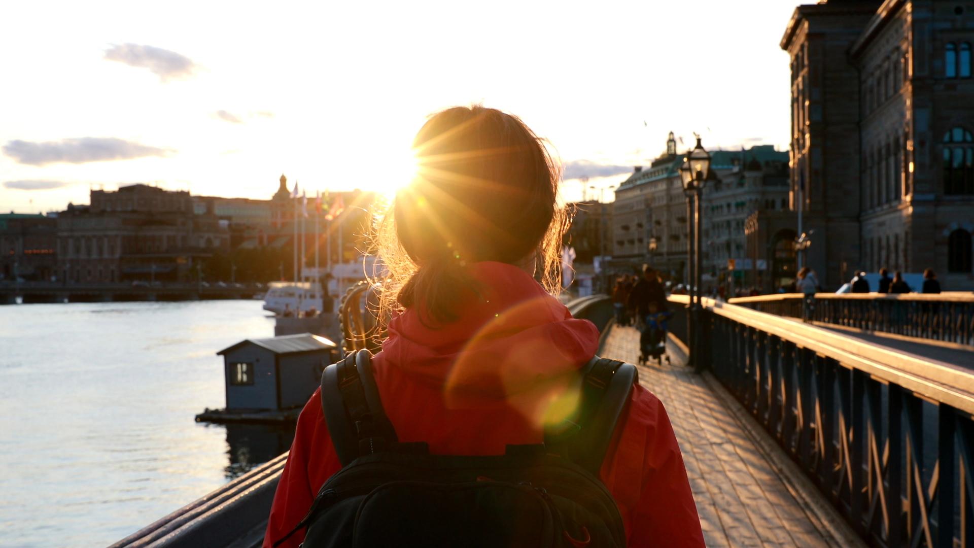 Kvinna som går mot Blasieholmen i Stockholm i solnedgången.